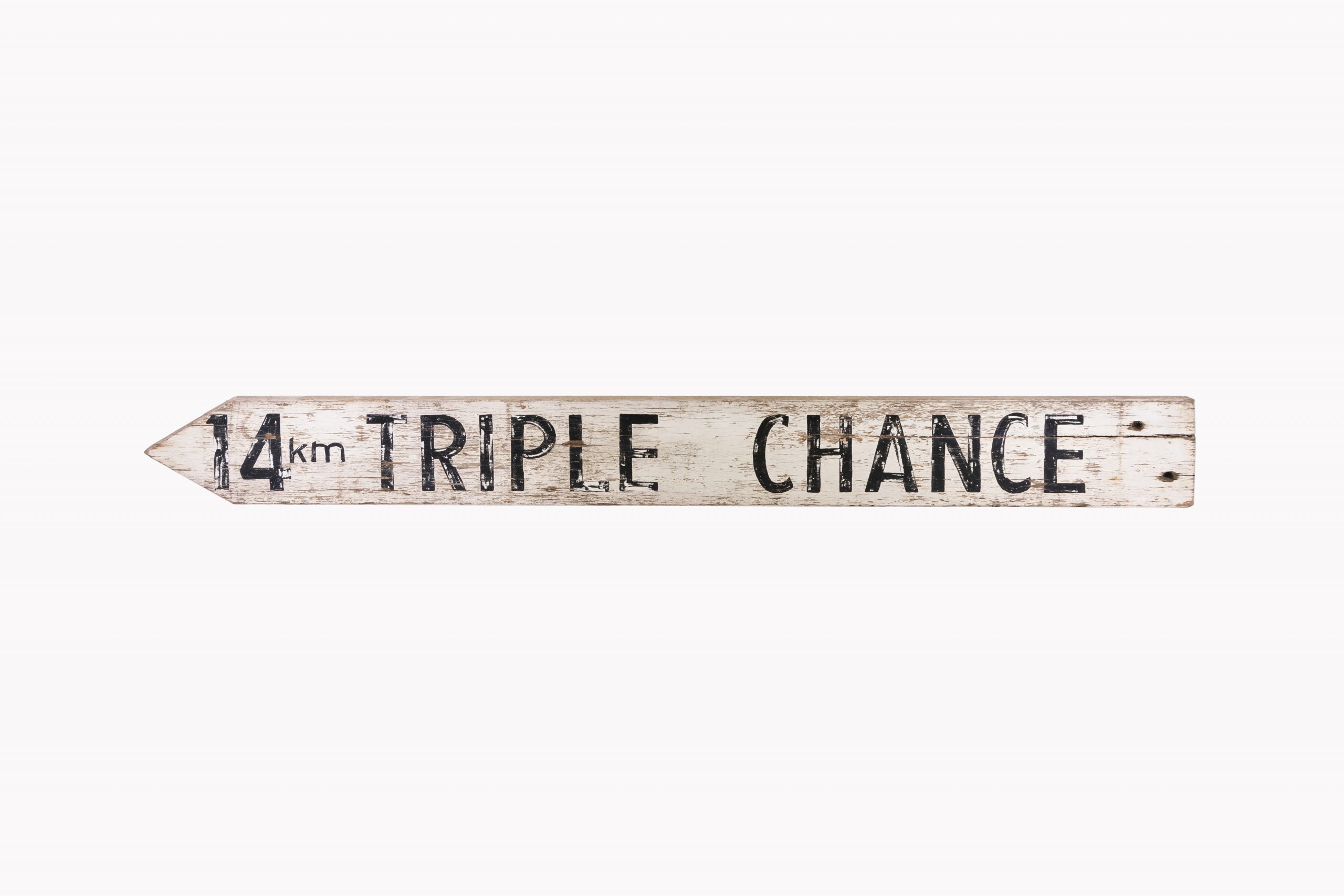 white directional sign with black lettering reading '14KM TRIPLE CHANCE'