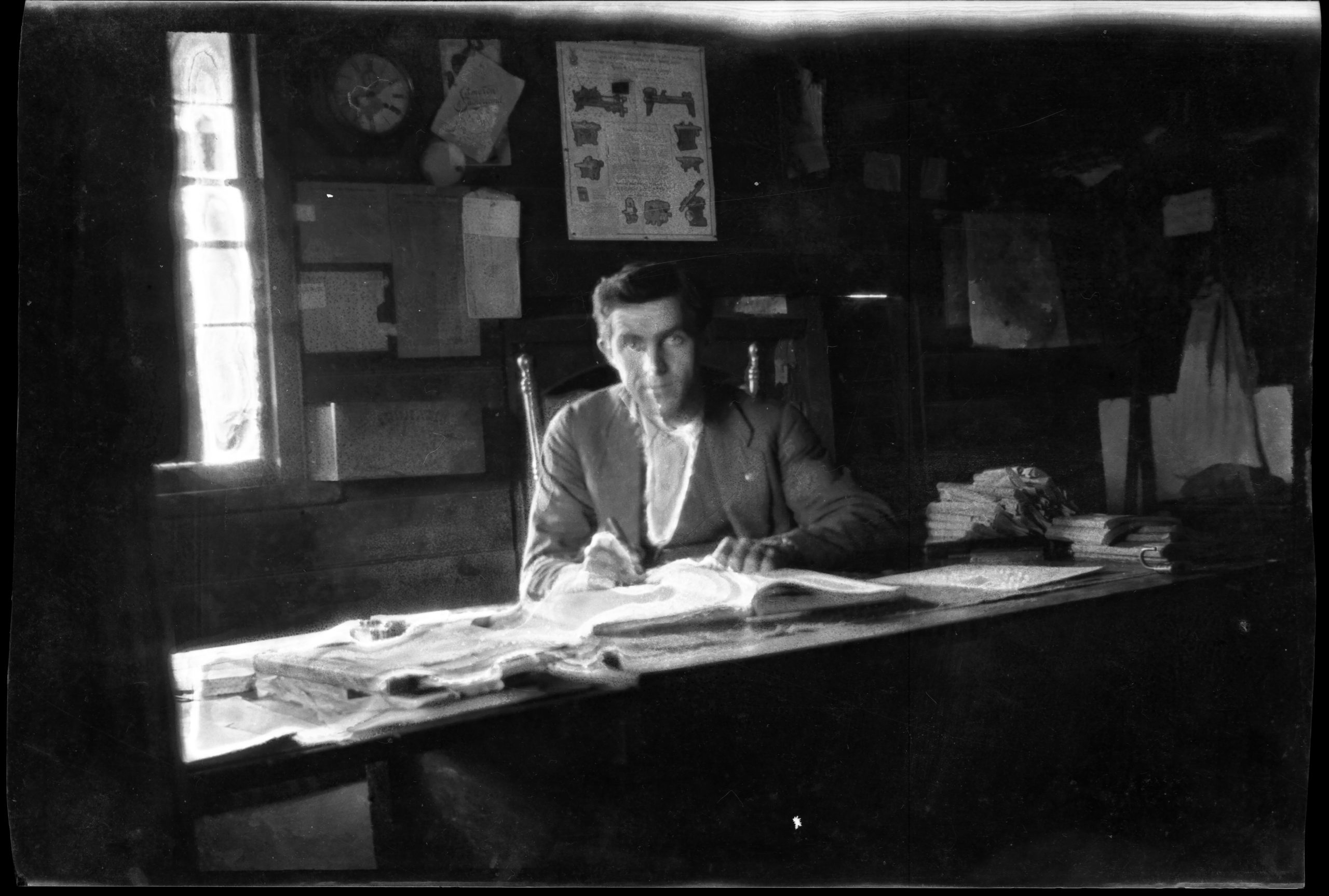 black and white photograph of man in a suit seated writing at a desk