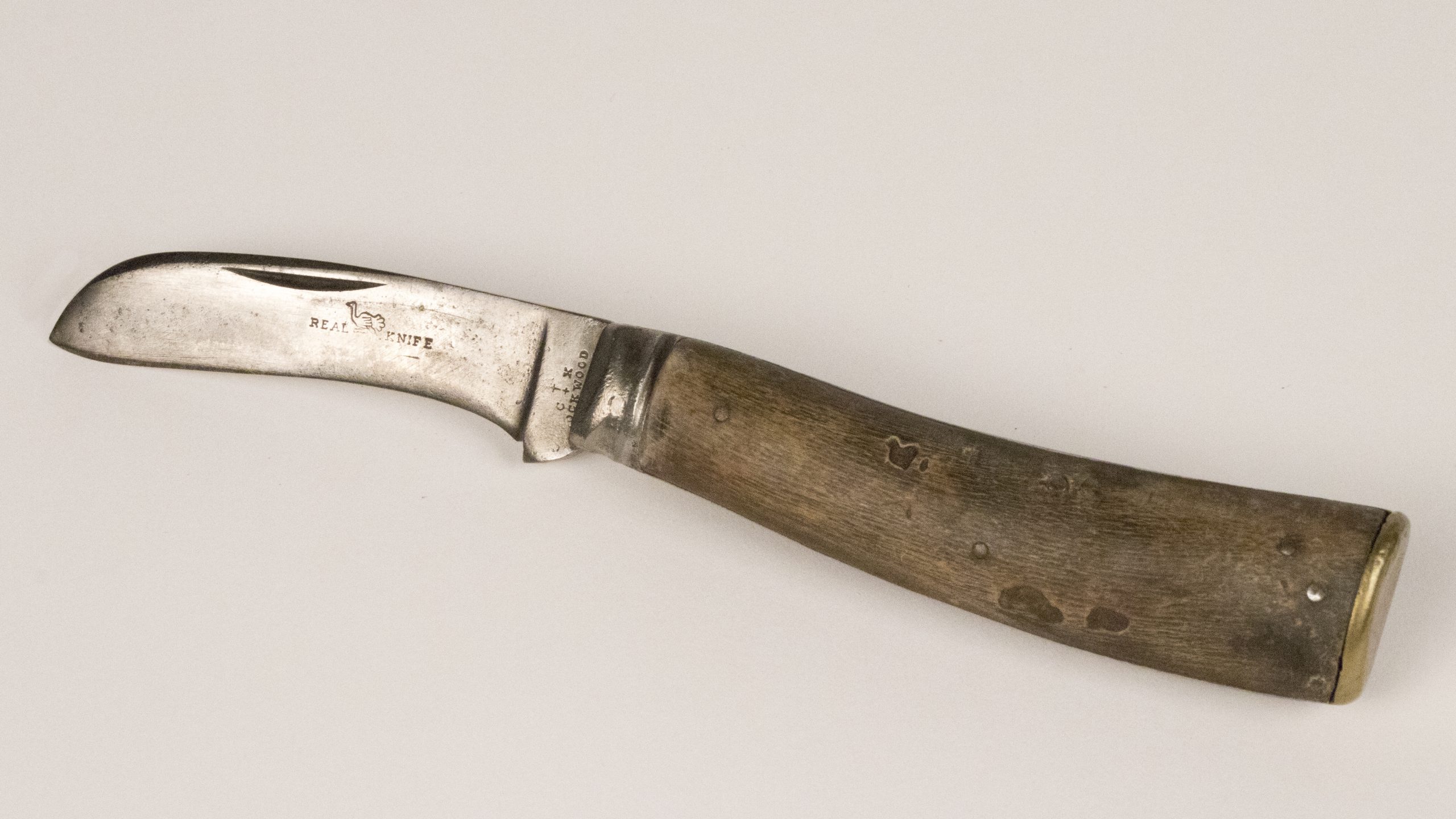 small curved knife with wooden hilt, it has a bird logo engraved into the metal