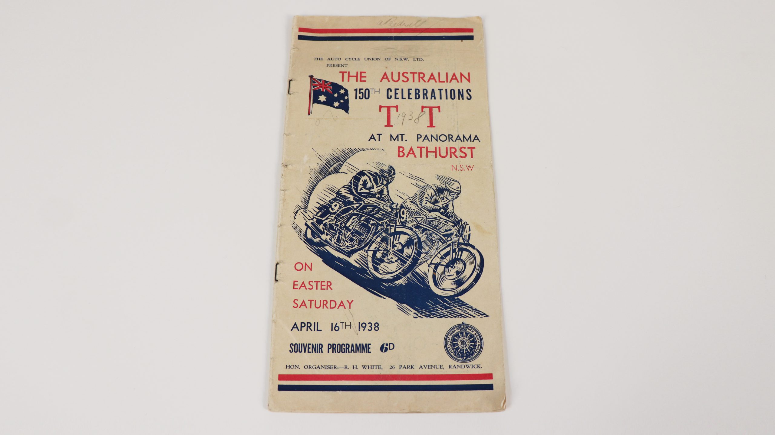 aged souvenir programme with illustrative cover of two motorcyclists named 'THE AUSTRALIAN 150TH CELEBRATIONS T T AT MT. PANORAMA BATHRUST NSW ON EASTER SUNDAY APRIL 16TH 1938'