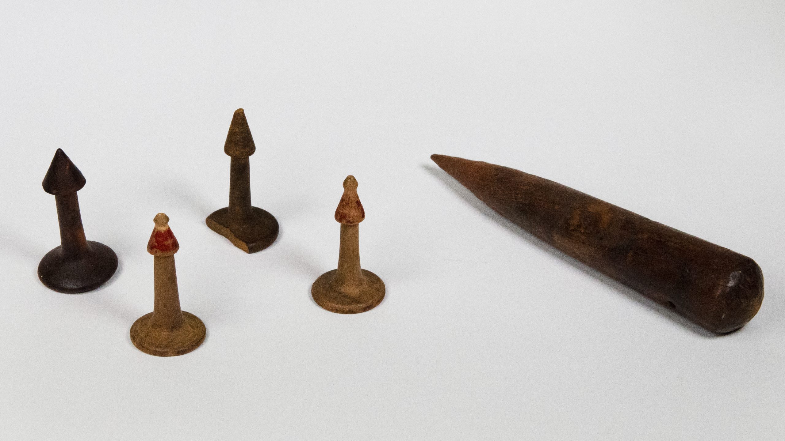 wooden spike beside four wooden nose pegs which look like cylinder with a flared base and a conical top