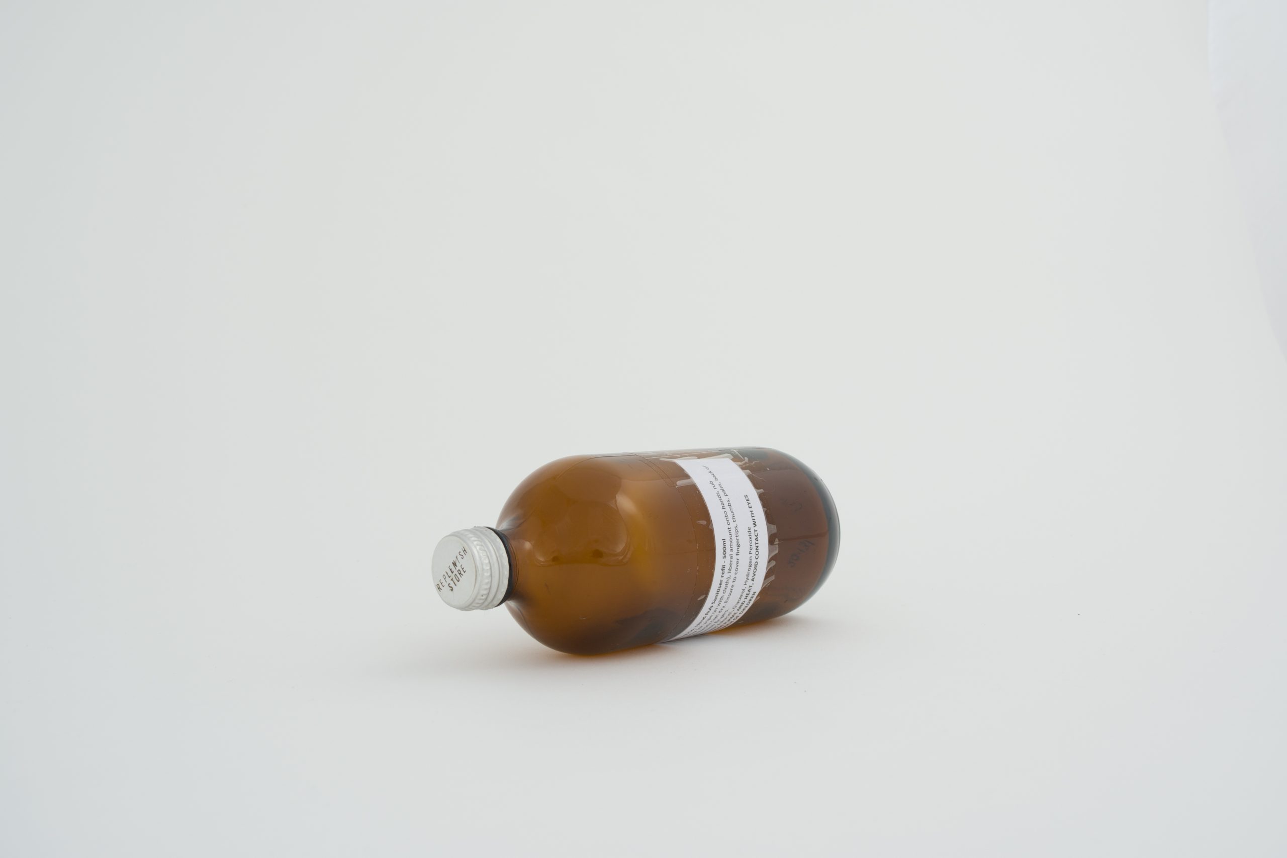 amber glass hand santiser bottle with white label and metal top