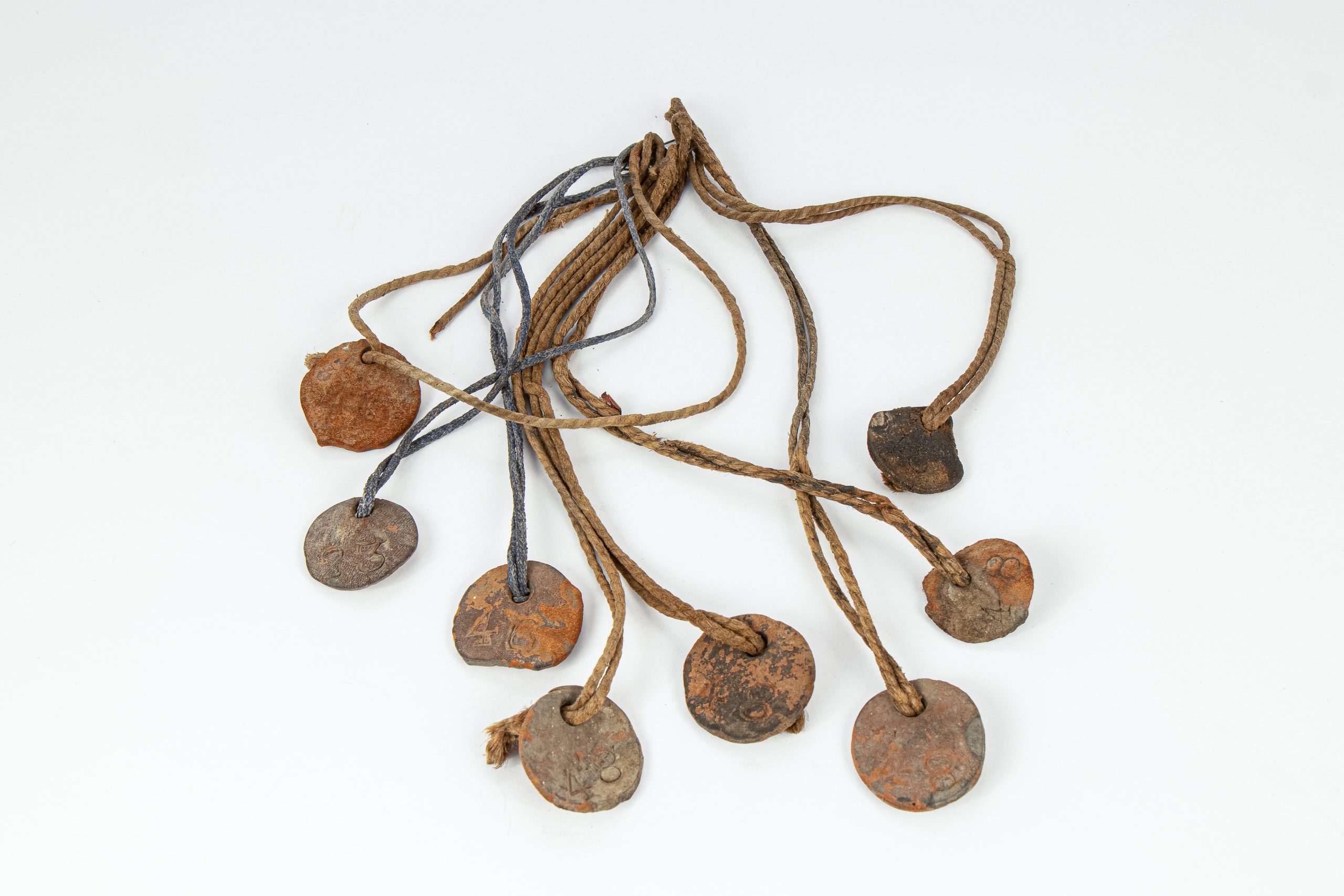 eight circular, aged leather tags attached together by twine