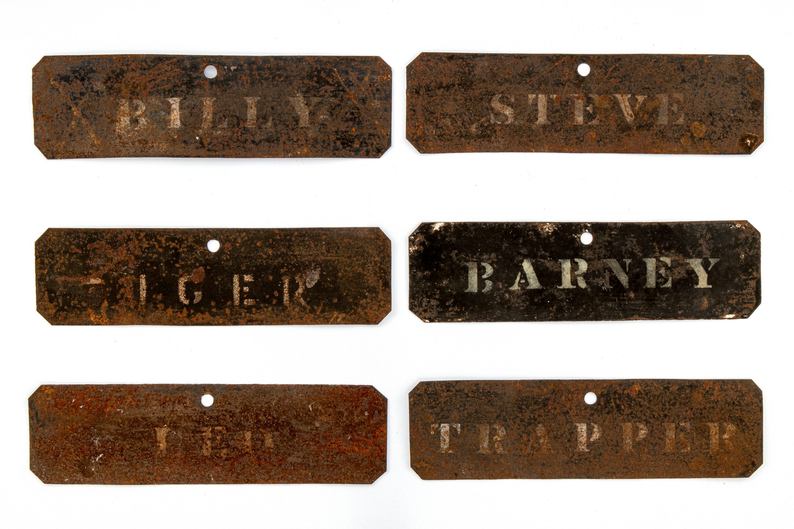 rusted metal name plates reading Billy, Steve, Tiger, Barney, Ted, and Trapper