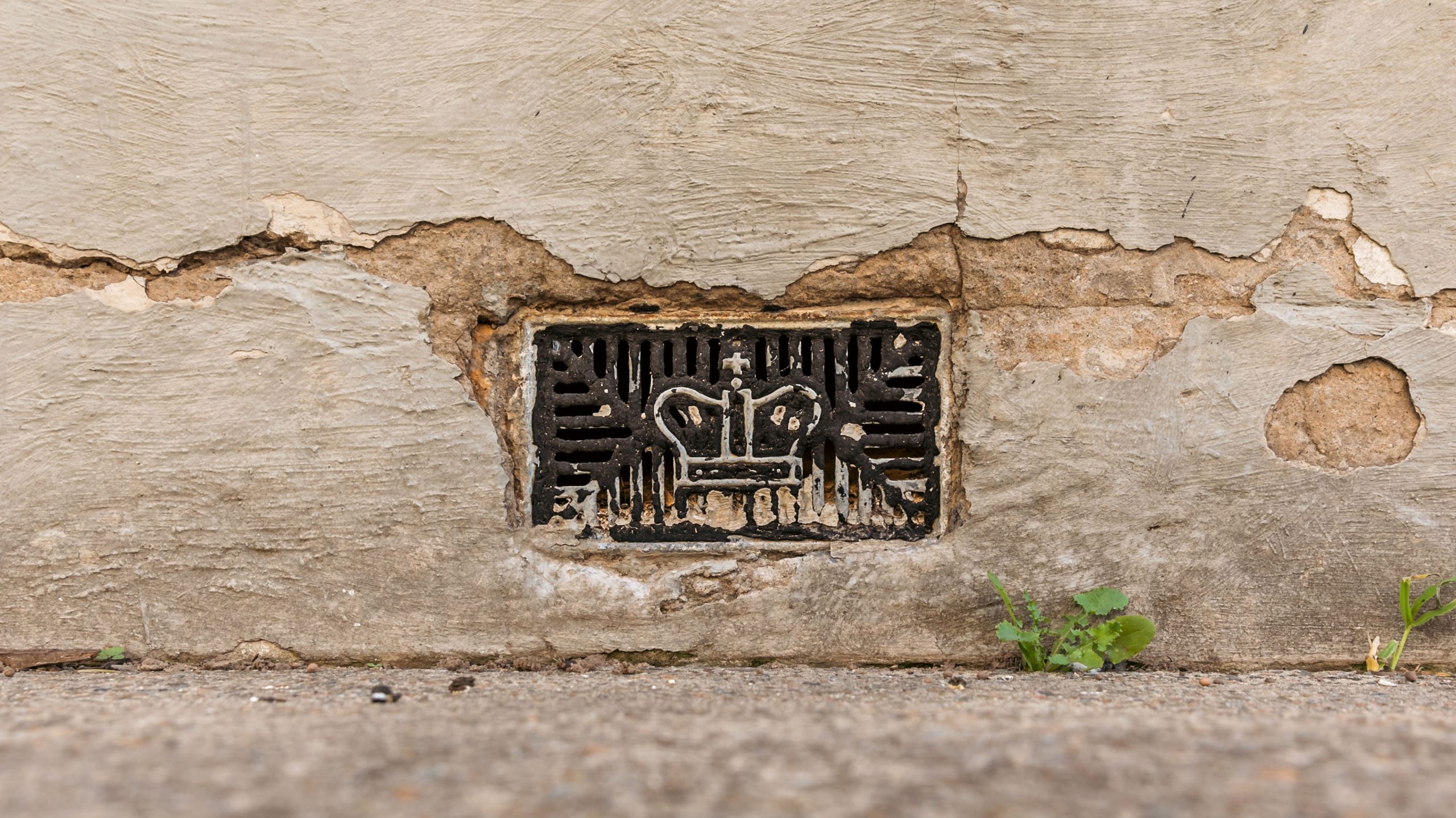 metal grill embedded in brick wall, it has a crown design