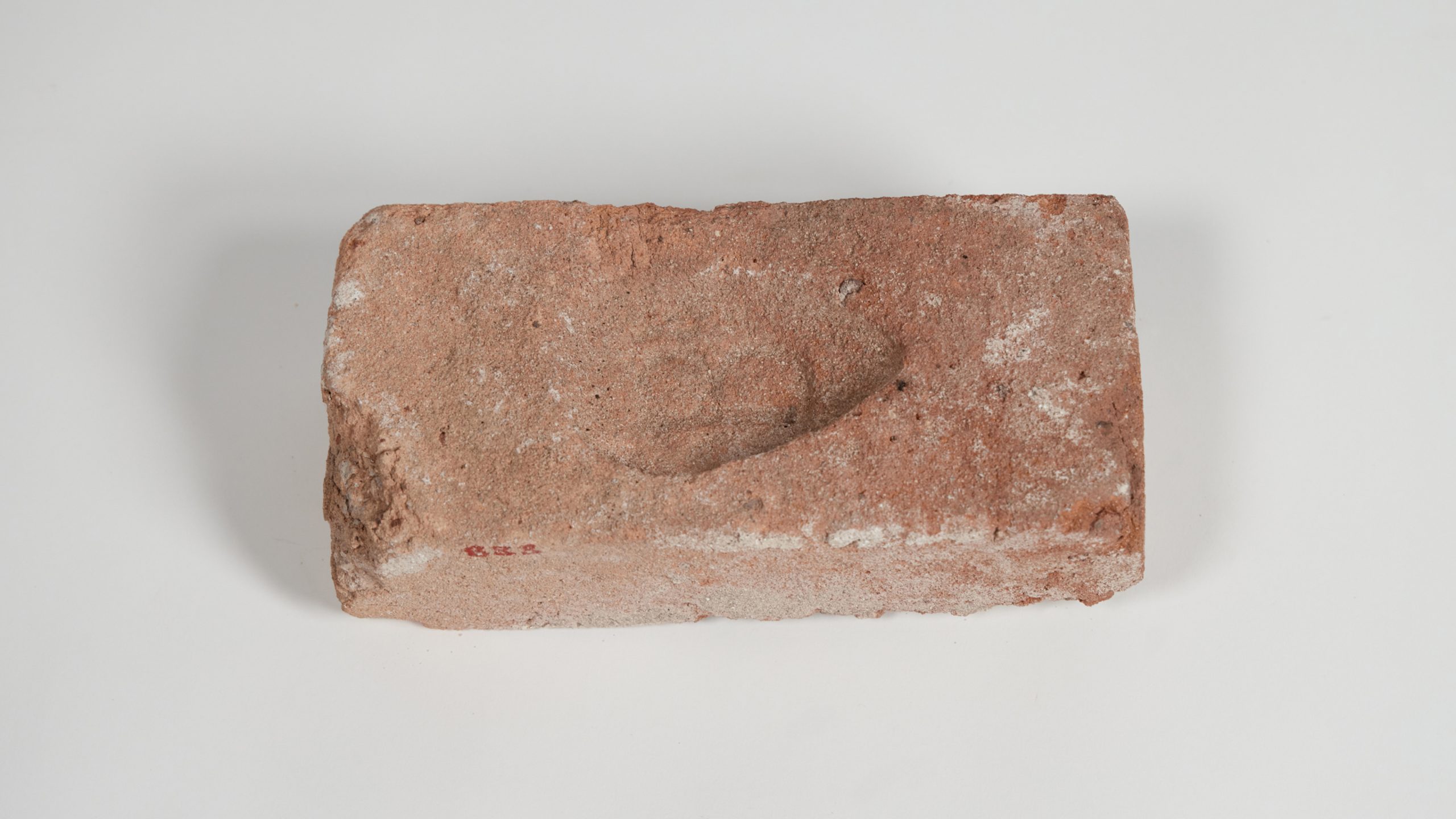 Chipped, dusty red, sandstone brick