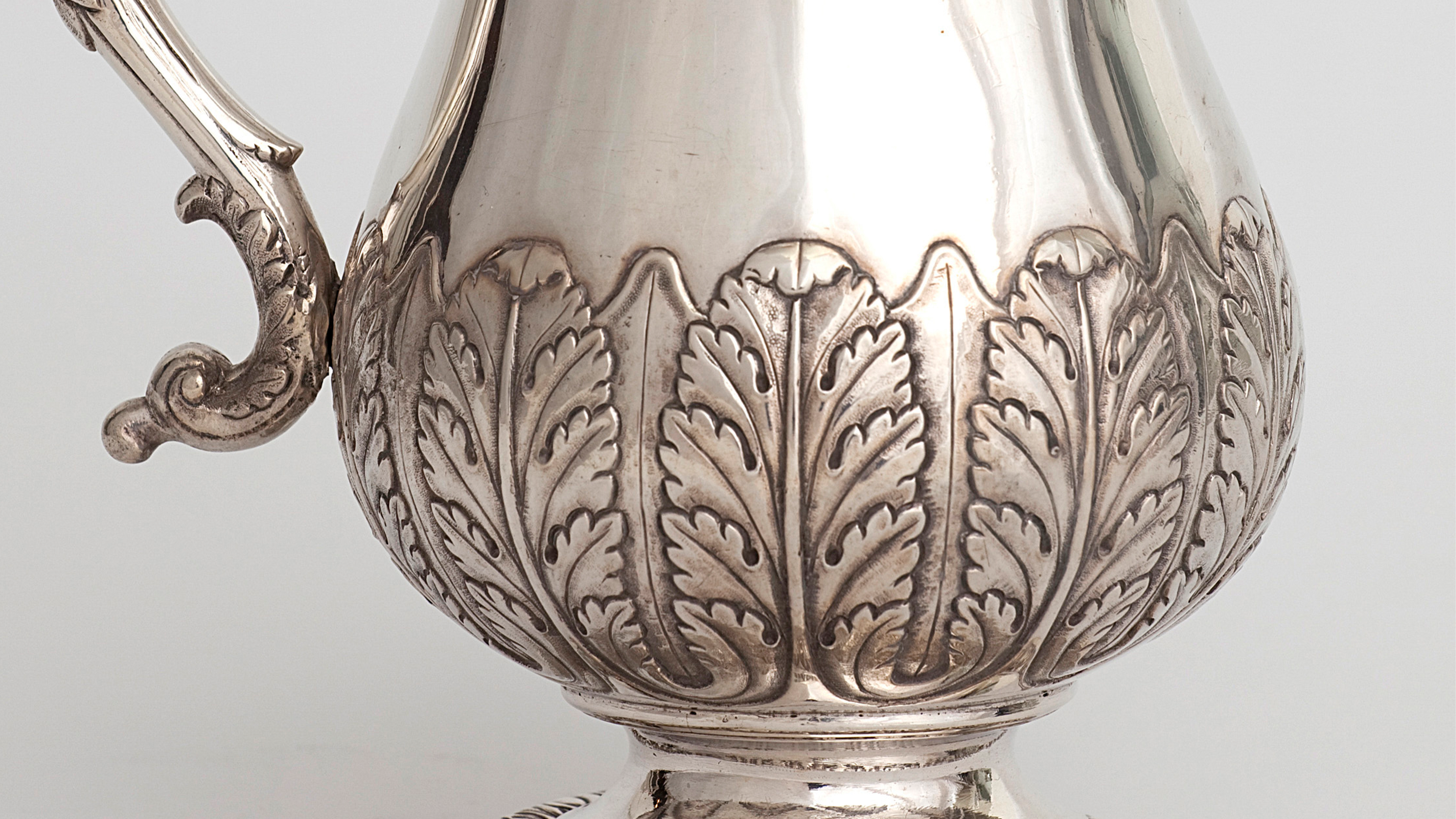 Close up of a silver tankard embellished with leafy design