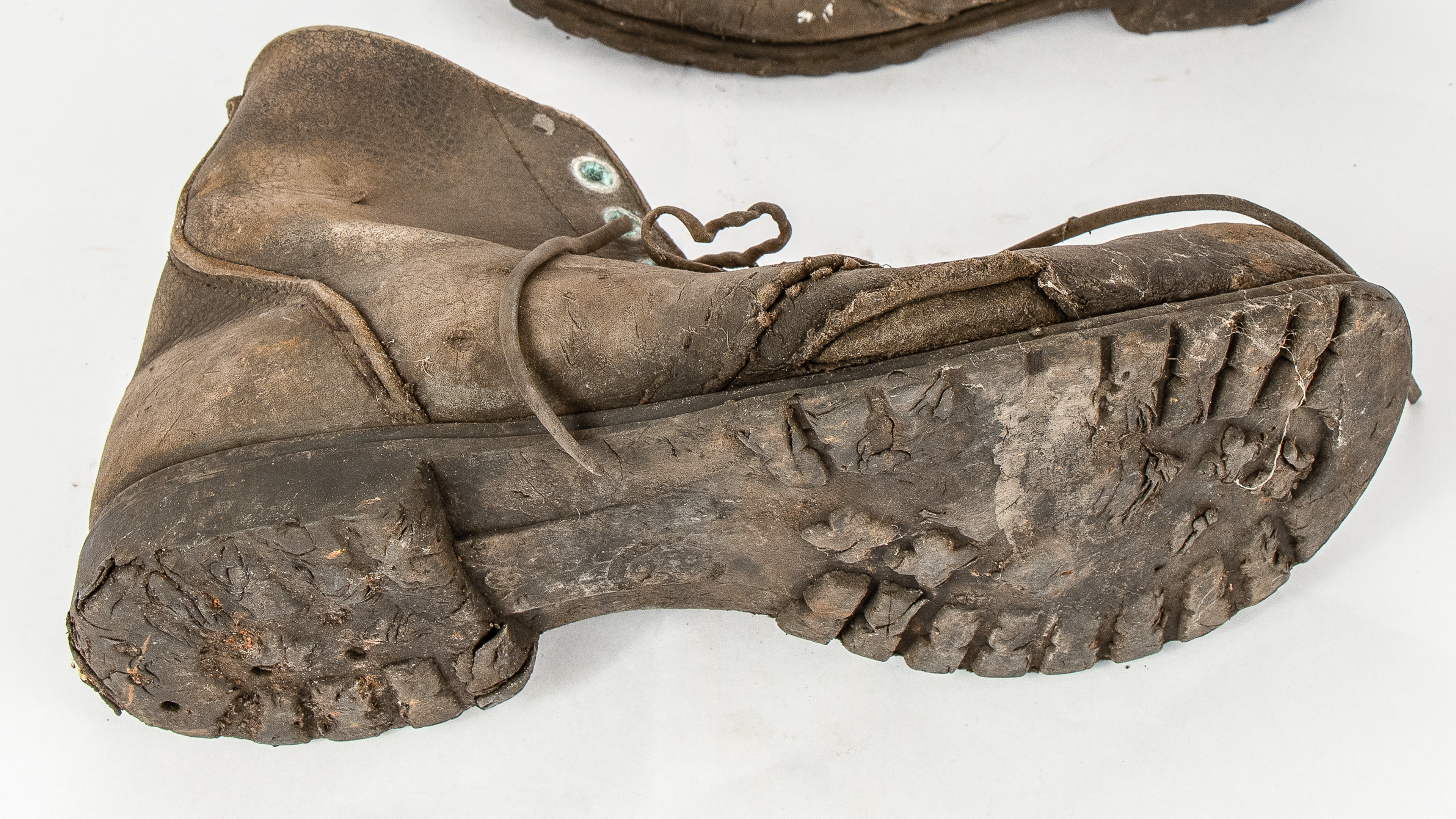 Dirty work boot laying on its side with worn down soles