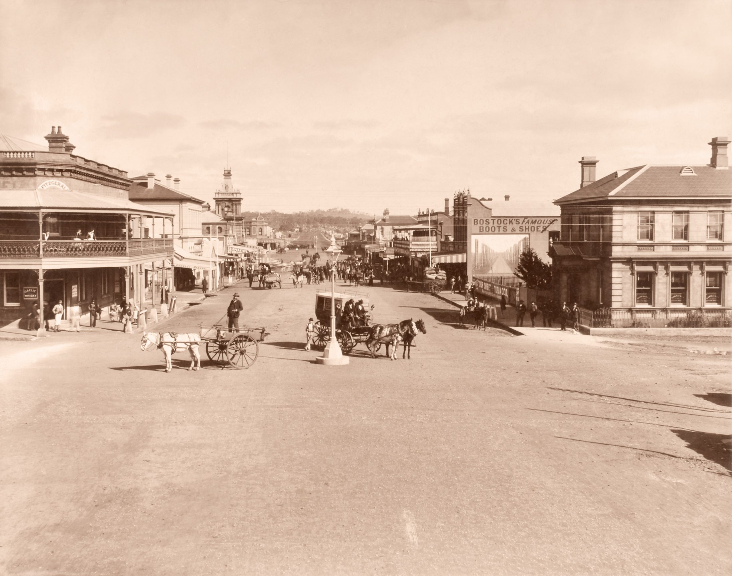 sepia-tone photograph pf the main street of Glen Innes, it has wide dirt roads with horse-drawn carriages